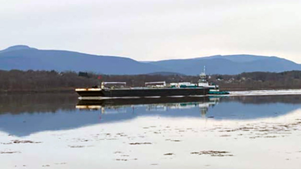 A barge on a river with mountains in the background.